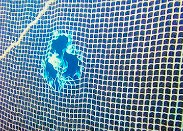 Bilde av hull i en notvegg fra en oppdrettsmerd tatt under vann. Hullet ble laget av en undervannsfarkosts fremdriftssystem, såkalte thrustere. Foto: © Virksomheten.
