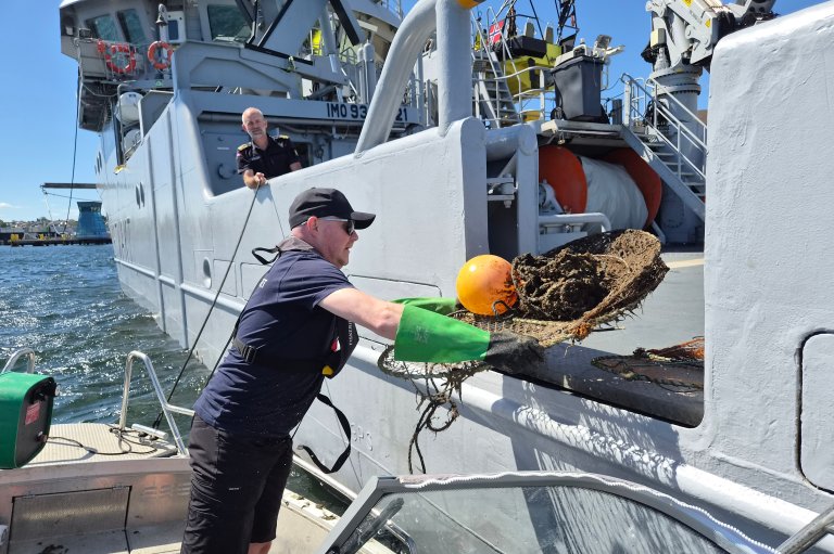 Inspektør fra Fiskeridirektoratet legger beslaglagte teiner om bord i kystvaktskipet KV Nornen. Foto: Marit Winther-Janson / SNO.
